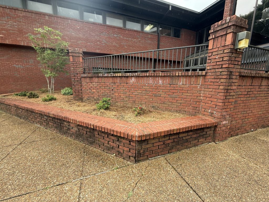 Brick retaining wall before cleaning, second angle, at Hospice Family Care in Huntsville, AL